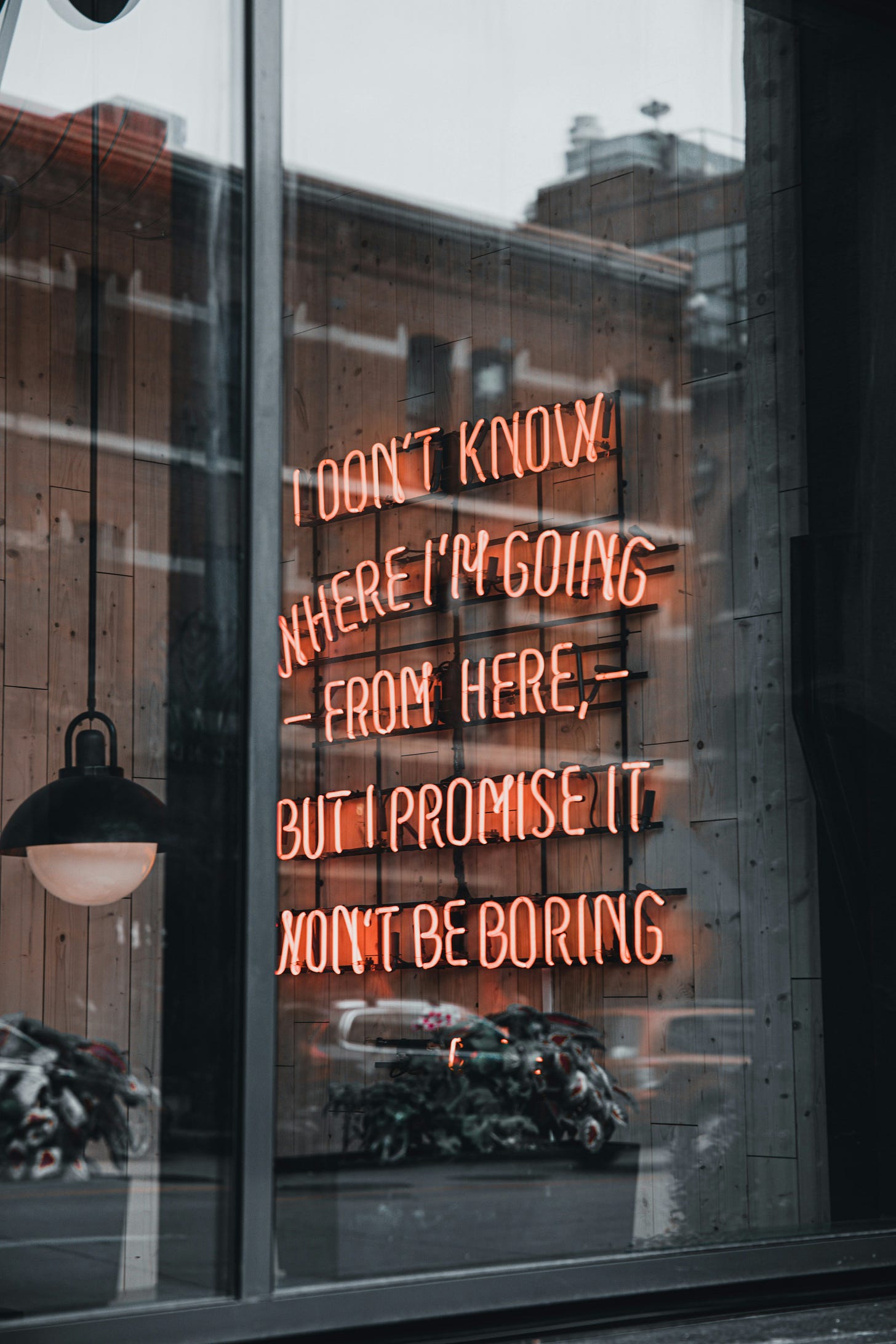 Neon Sign through window reads "I don't know where I'm going from here but I know it won't be boring"