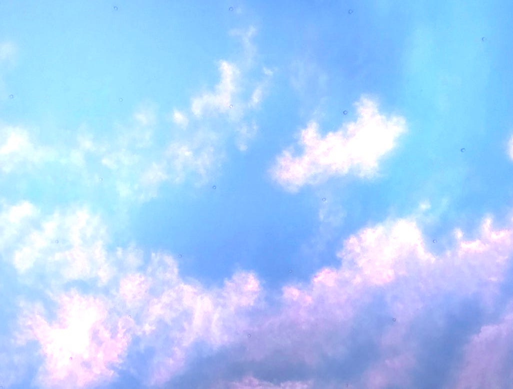 A blue sky with wispy clouds highlighted pink and purple