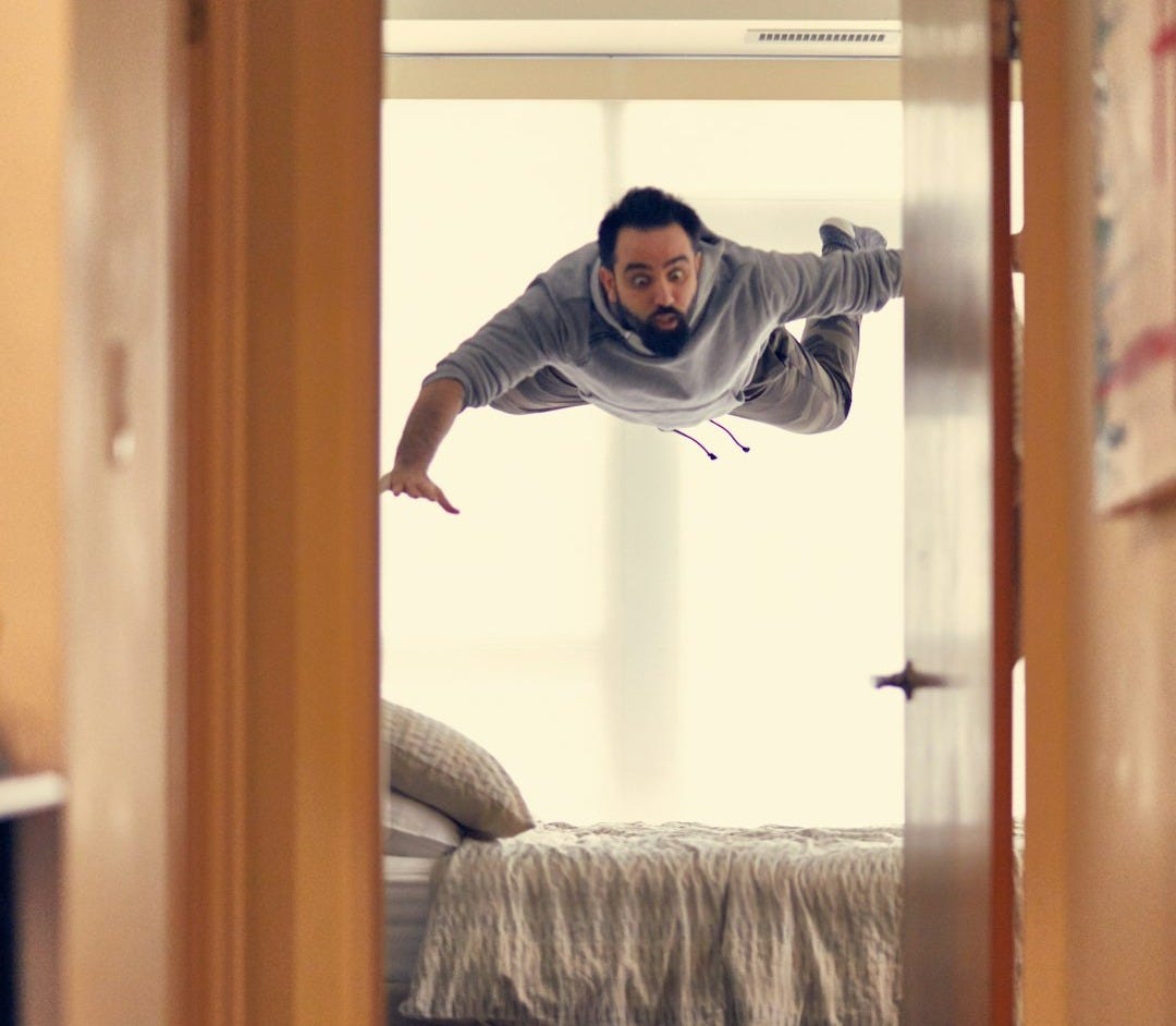 man falling from ceiling on bed