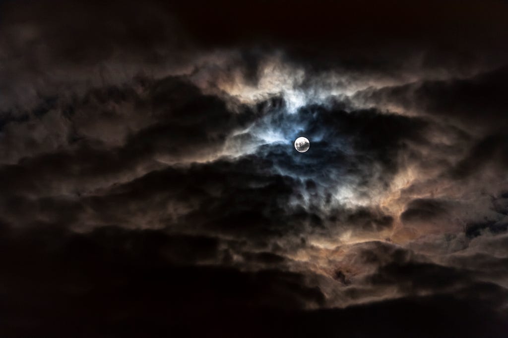 the moon shining through some clouds at night