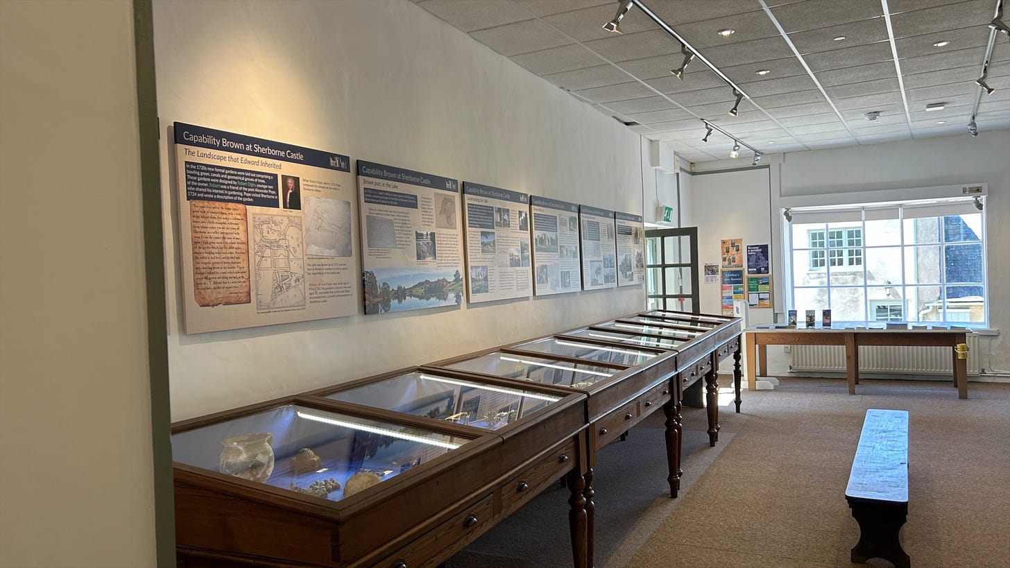 The museum has many display cabinets as seen in the photo. On the wall there are information boards relating the history of Sherborne Castle and Gardens. There is a wooden bench seat for visitors. Image: Roland's Travels.
