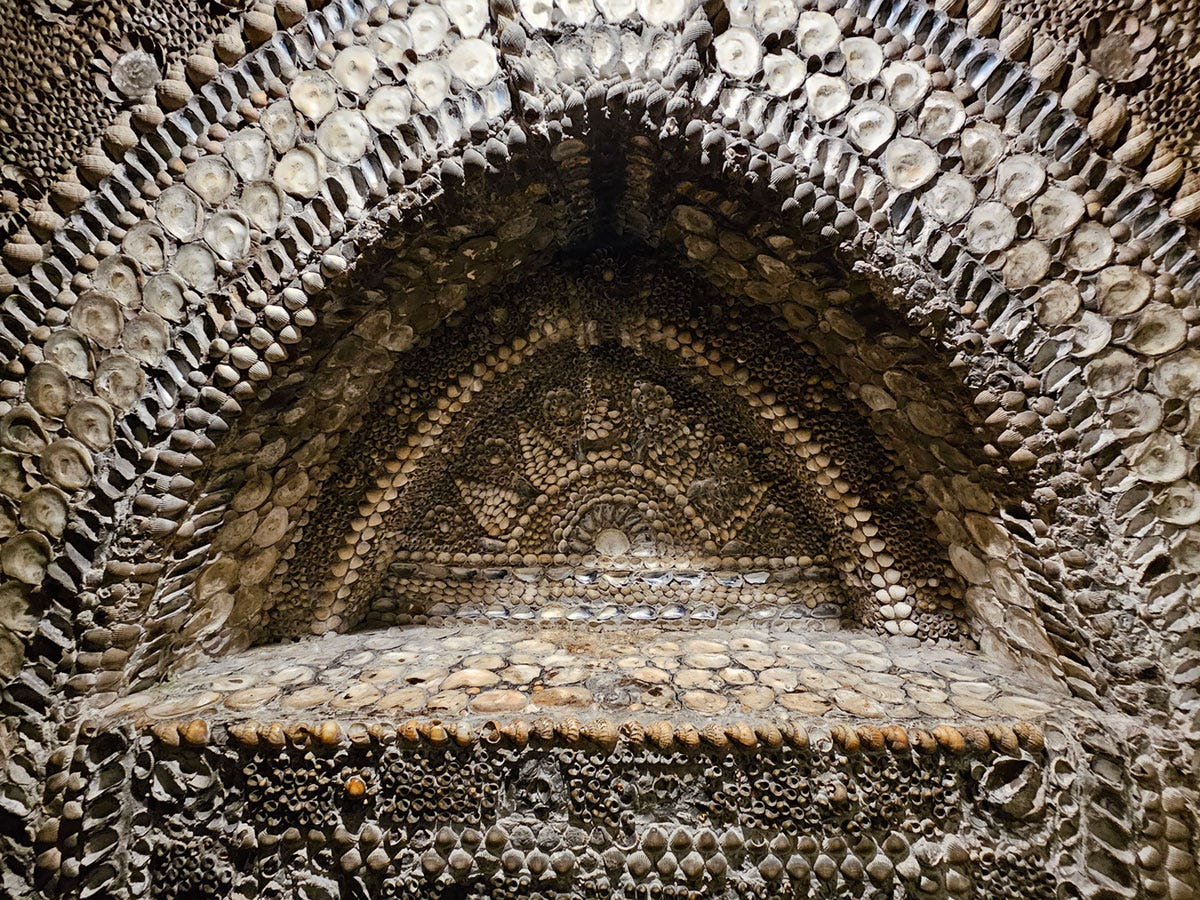 A dome-shaped niche in a wall. ALl surfaces are completely covered in shells.