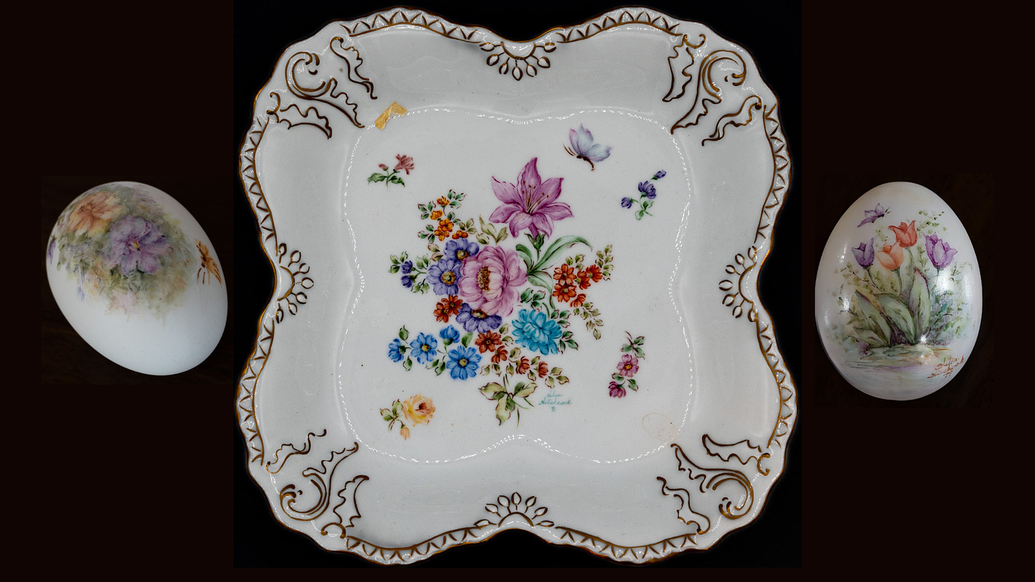 Photo of three pieces of painted porcelain, easter egss on either side of a scalloped plate painted with blue, pink, and red flowers with gold leaf edging around the plate