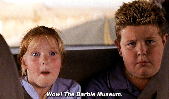 Cena do filme Tá Todo Mundo Louco em que duas crianças estão no banco de trás do carro e a menininha exclama: "Uau, o museu da Barbie!"