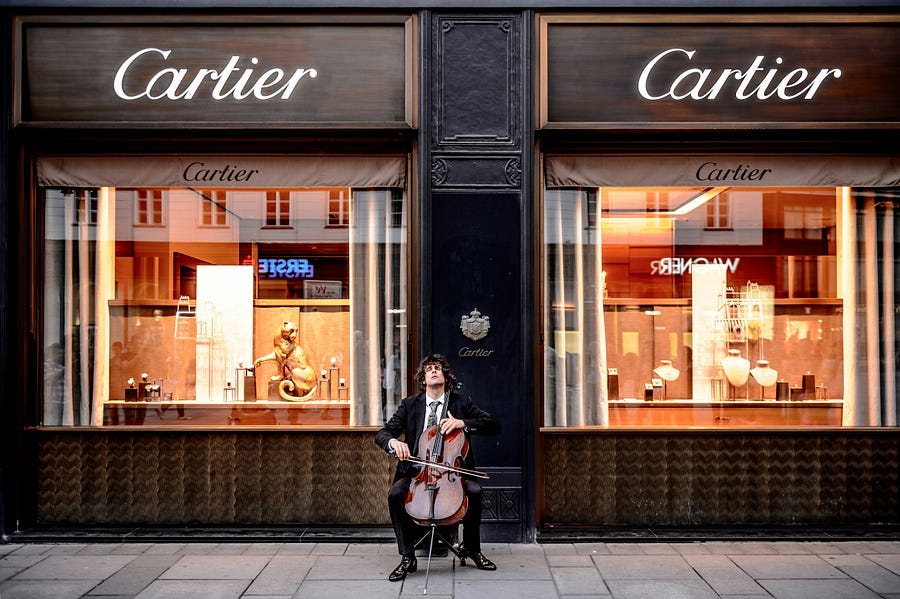 Cartier shop and shop wndows with cellist playing outside.