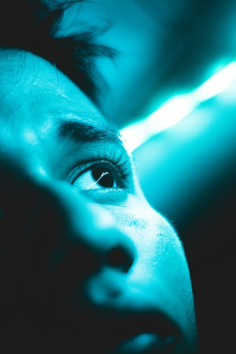 Face of a man looking upwards, a blue-tinted photo.