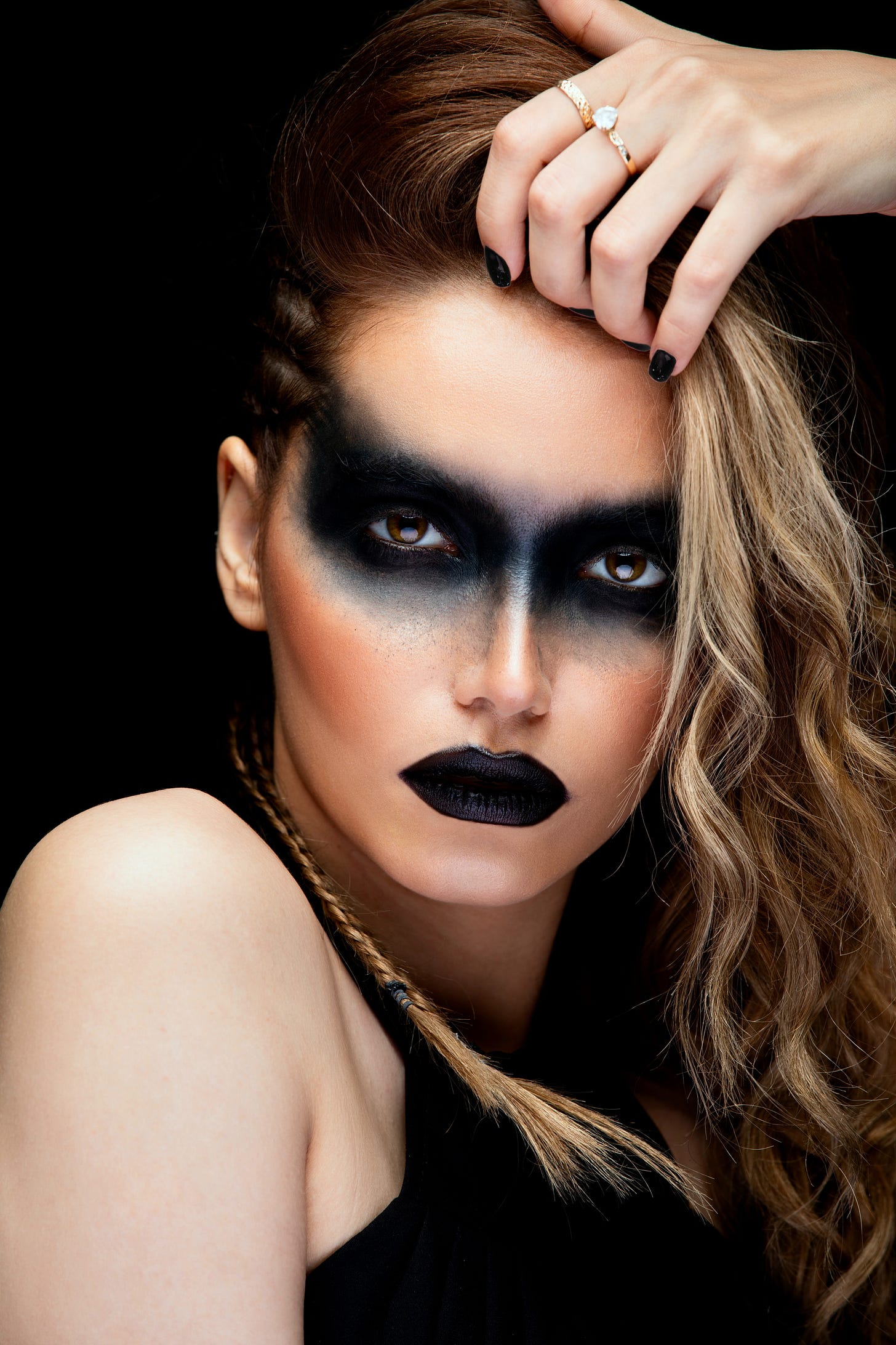 A portrait of a fair-skinned woman with black makeup surrounding her eyes and black lipstick.