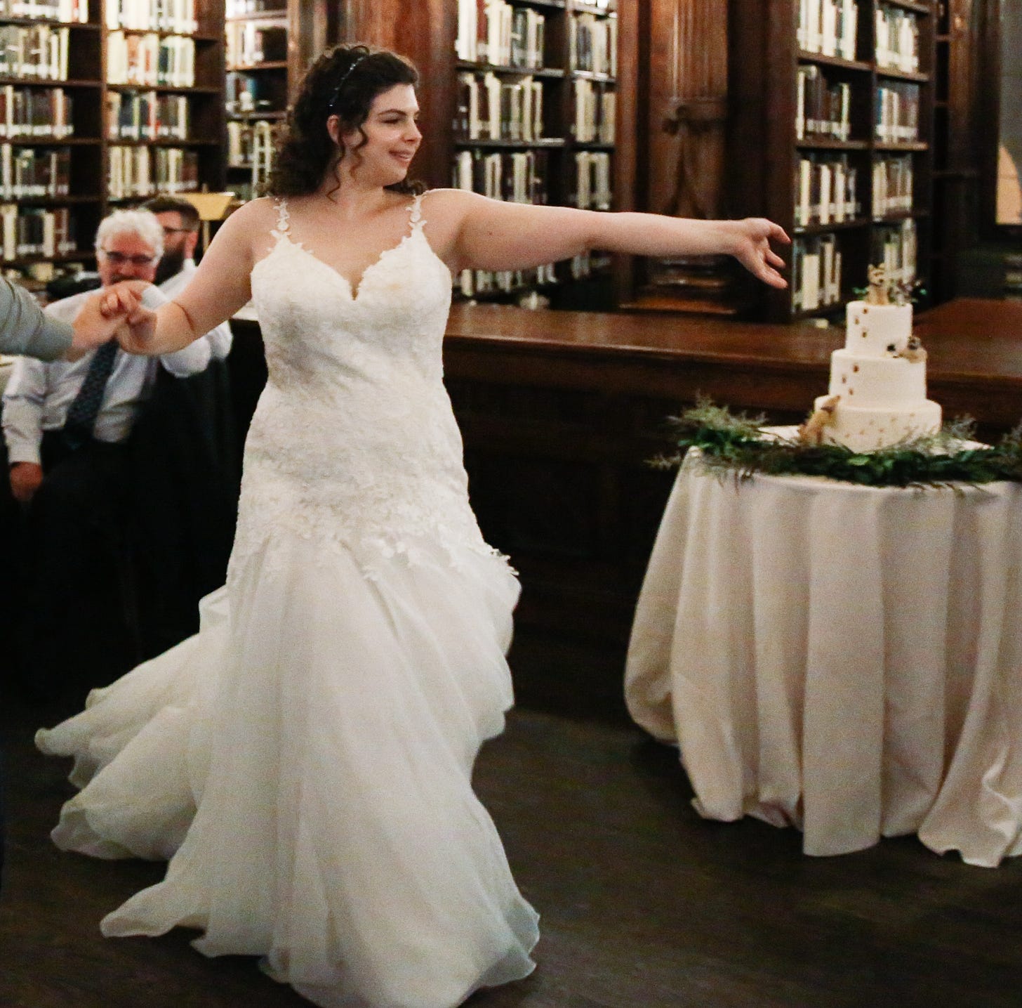 A woman in a wedding dress dances in a library
