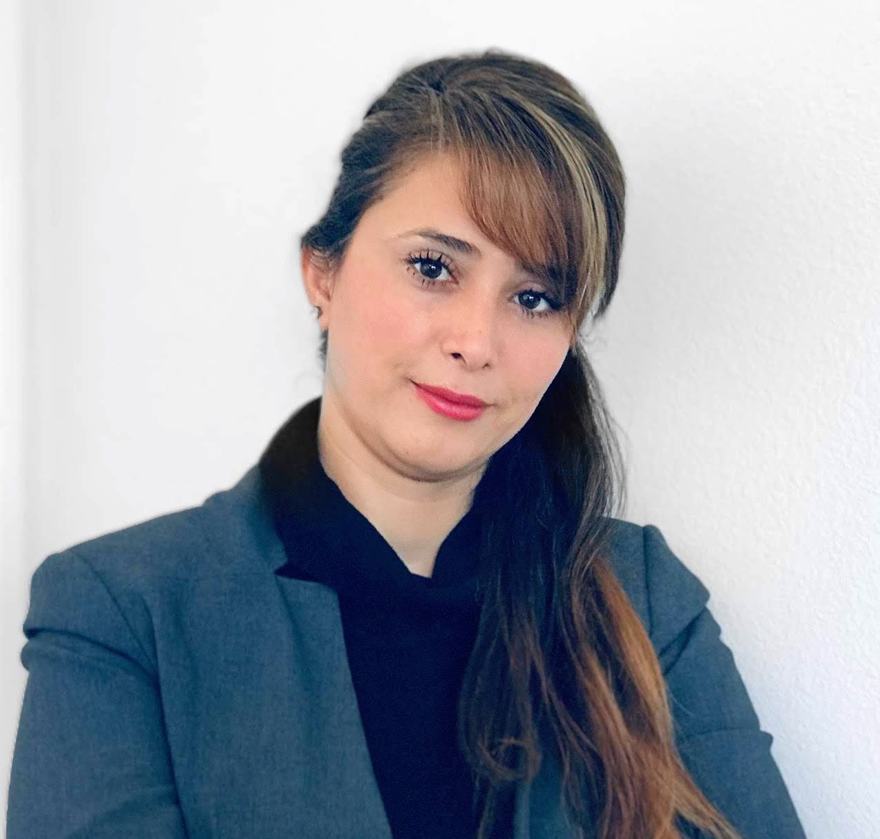 a headshot of a woman with long hair, wearing a light blue blazer and a dark blue blouse