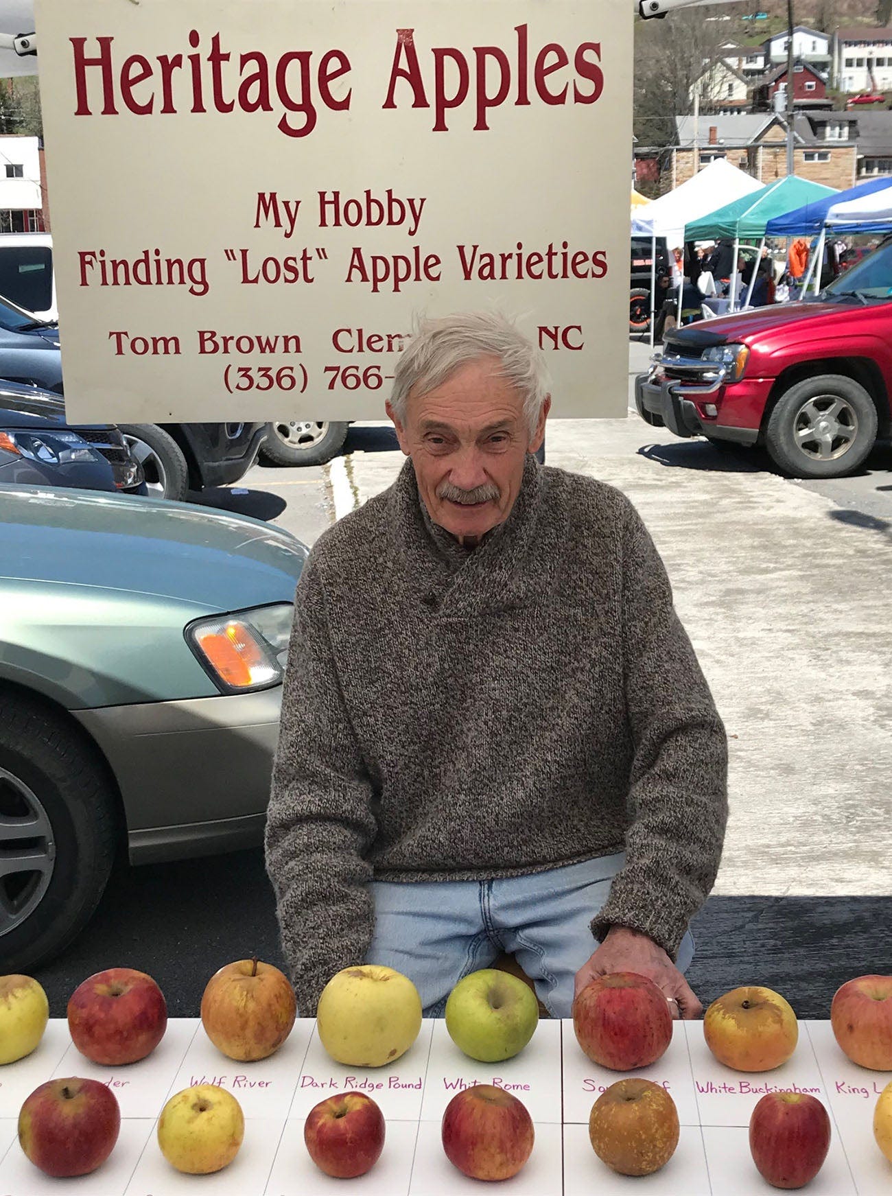 Tom Brown - Adsum - Older man sitting in front of a table of heritage apple varieties