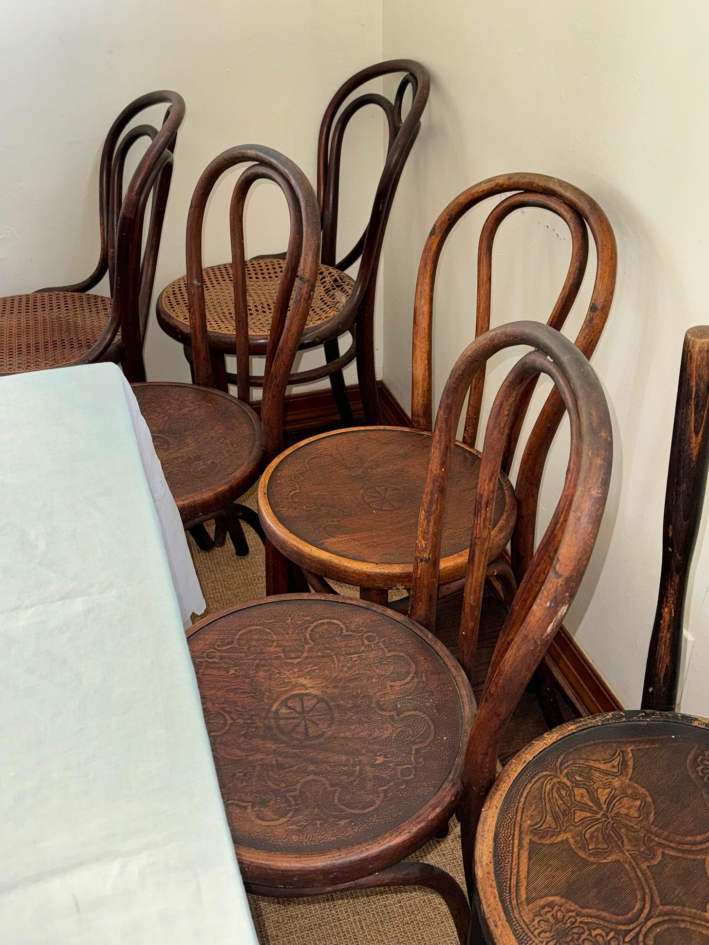 6 bentwood chairs arranged in a corner of a room.