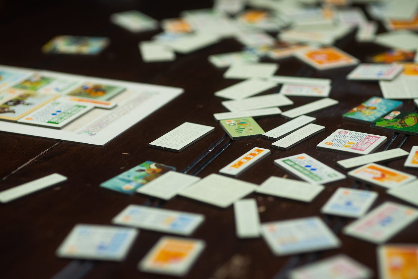 Tiles from the game Fit to Print are strewn across the table, with a newspaper board in the background.