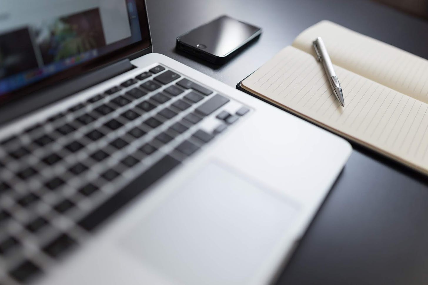 A black and white photo of a laptop and notebook