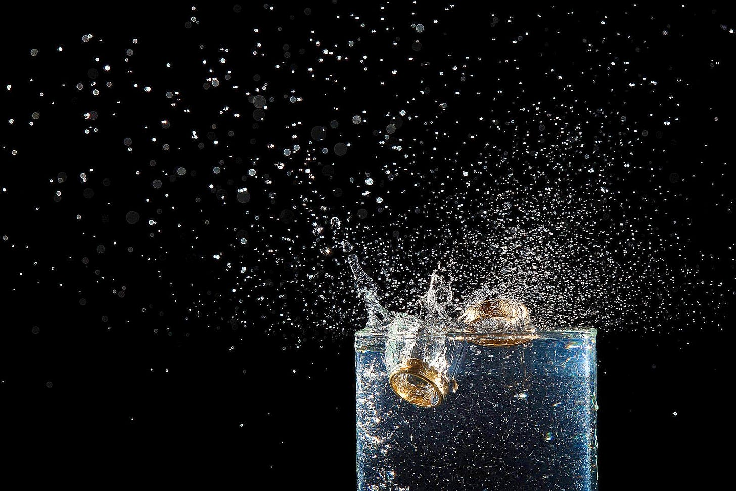 image of two wedding rings dropped in a glass of liquid, causing big splashes