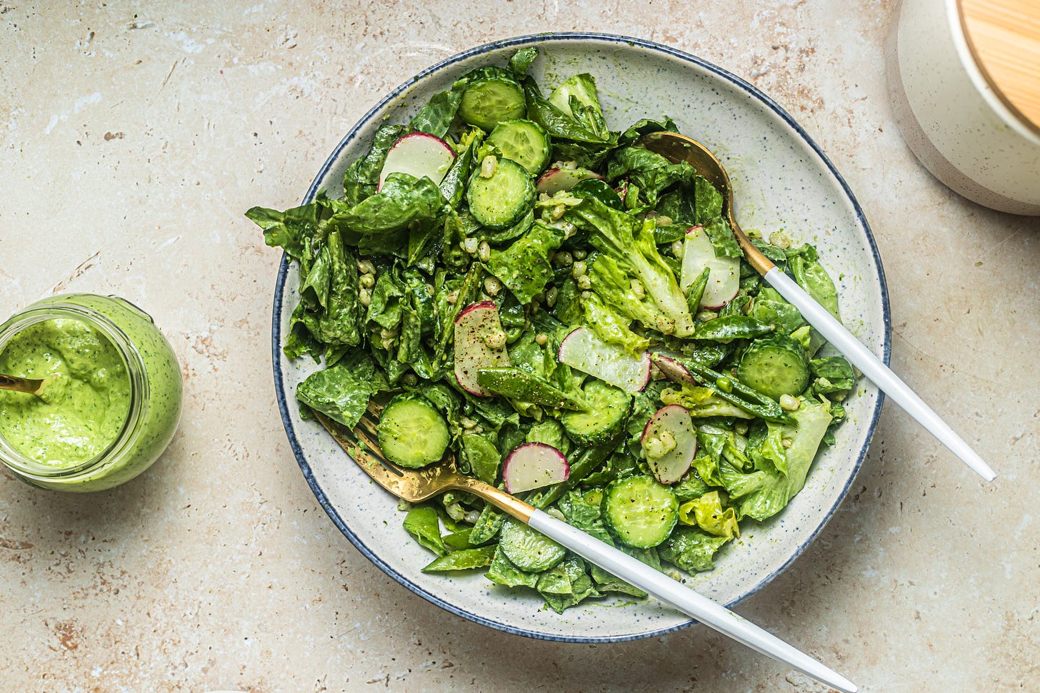 overhead shot of salad with cucumbers, lettuce, and radishes in a bowl