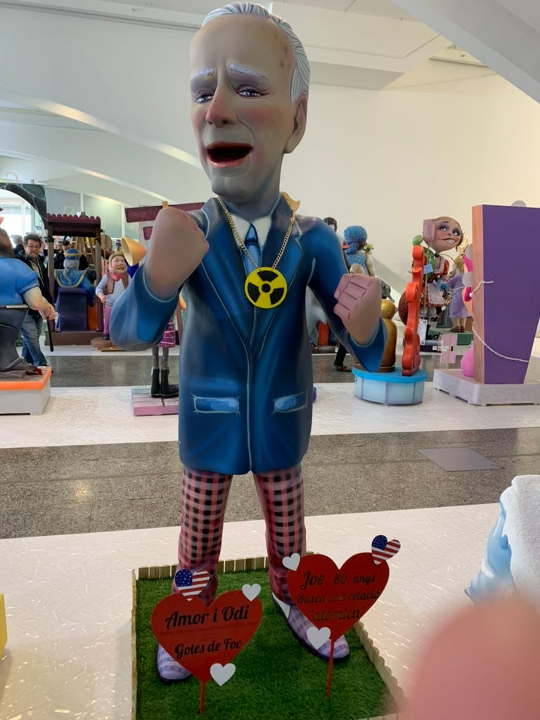 A ninot of Biden with a nuclear symbol hanging around his neck like a necklace