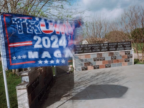 A red, white and blue Trump 2024 flag flies to the left of a memorial at the Waco site.