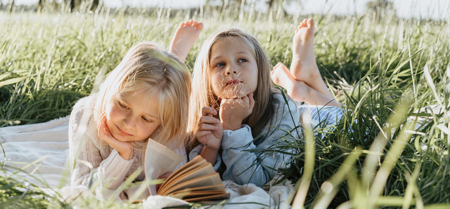 Two girls reading in a sunlit field Two girls reading in a sunlit field