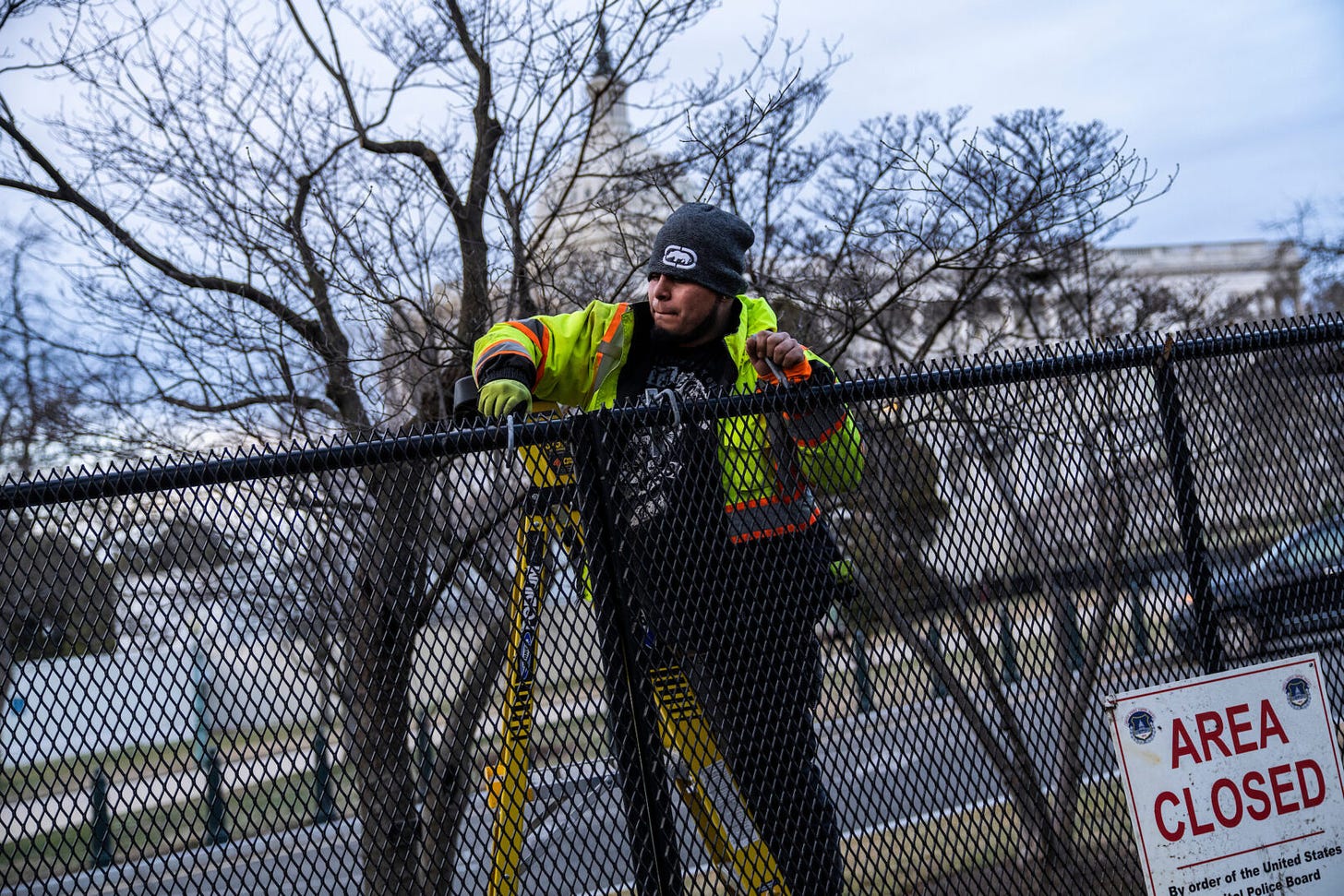 A worker installs a security fence that surrounds the Capitol in February 2023, ahead of President Joe Biden’s State of the Union address.