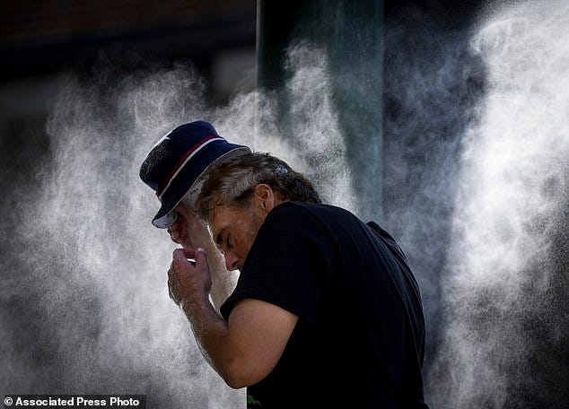 Health costs will come from people suffering from heat exposure, while work stoppages will impact businesses when it's too hot to work. Here, a man cools off at a temporary misting station in Vancouver, British Columbia, August 16, 2023