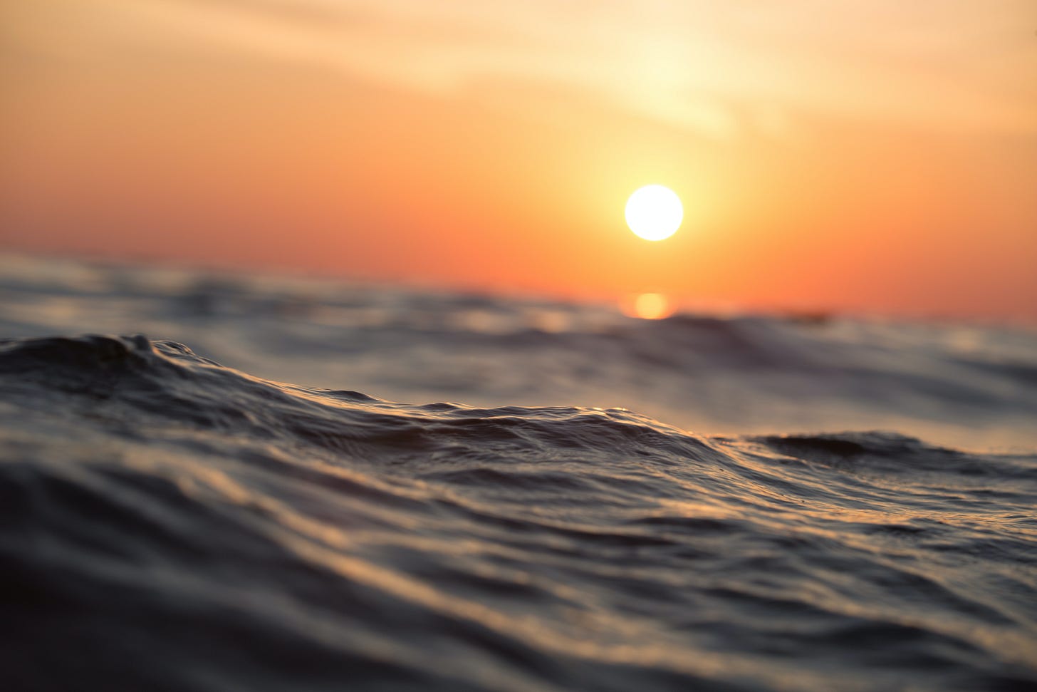close up ocean waves with an orange sunset in the background