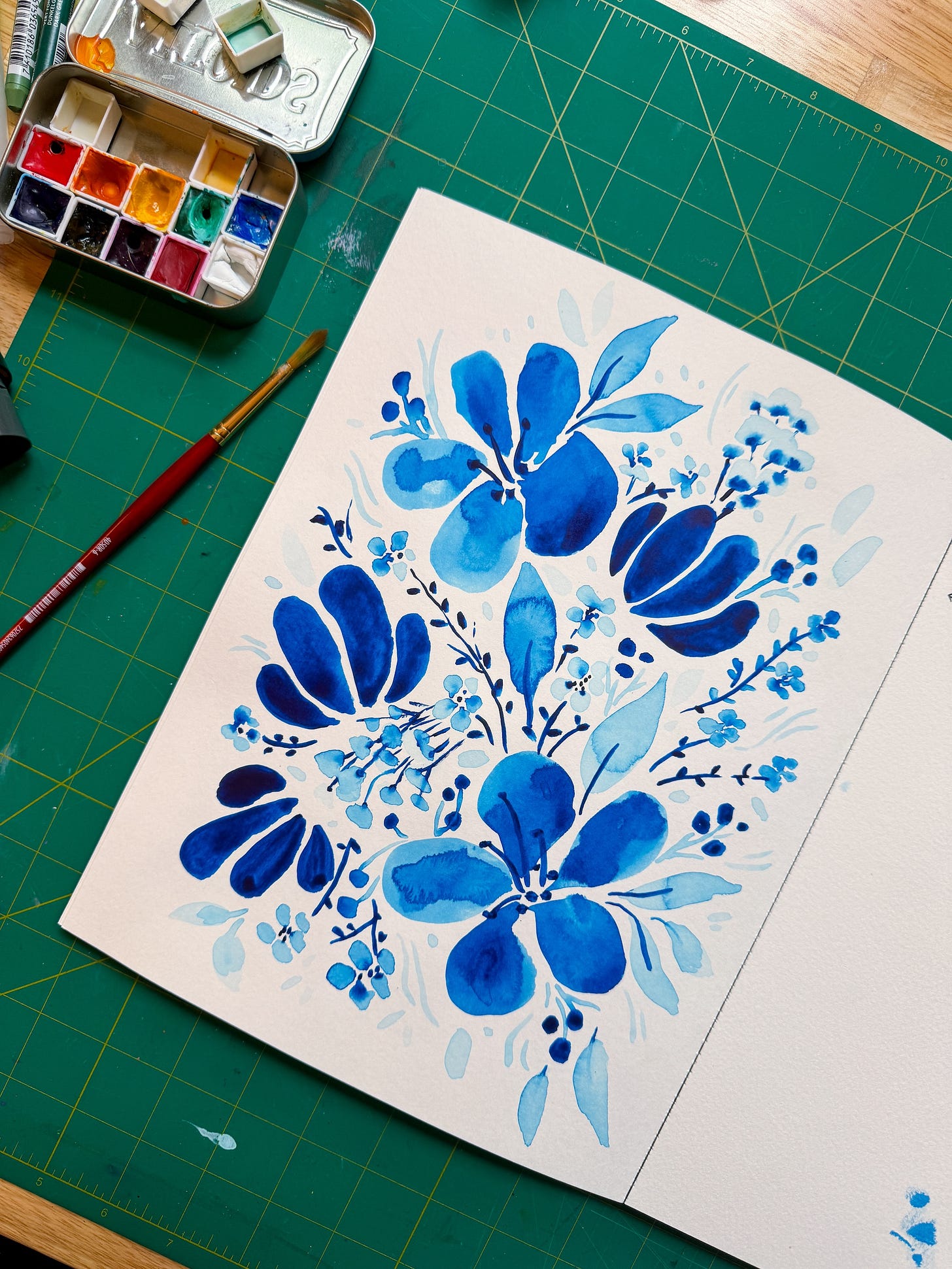 single sketchbook page with floral watercolor paintings in various shades of blue