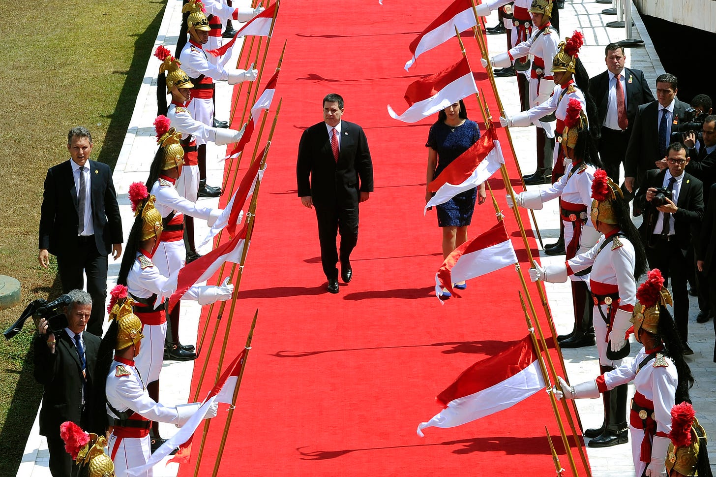 President of Paraguay Horacio Cartes walks on a red carpet with a platoon of uniformed flag bearers lining his route. Photo was taken  August 21, 2017 when Cartes was still president of Paraguay and was attending an event at the country's national Congress.