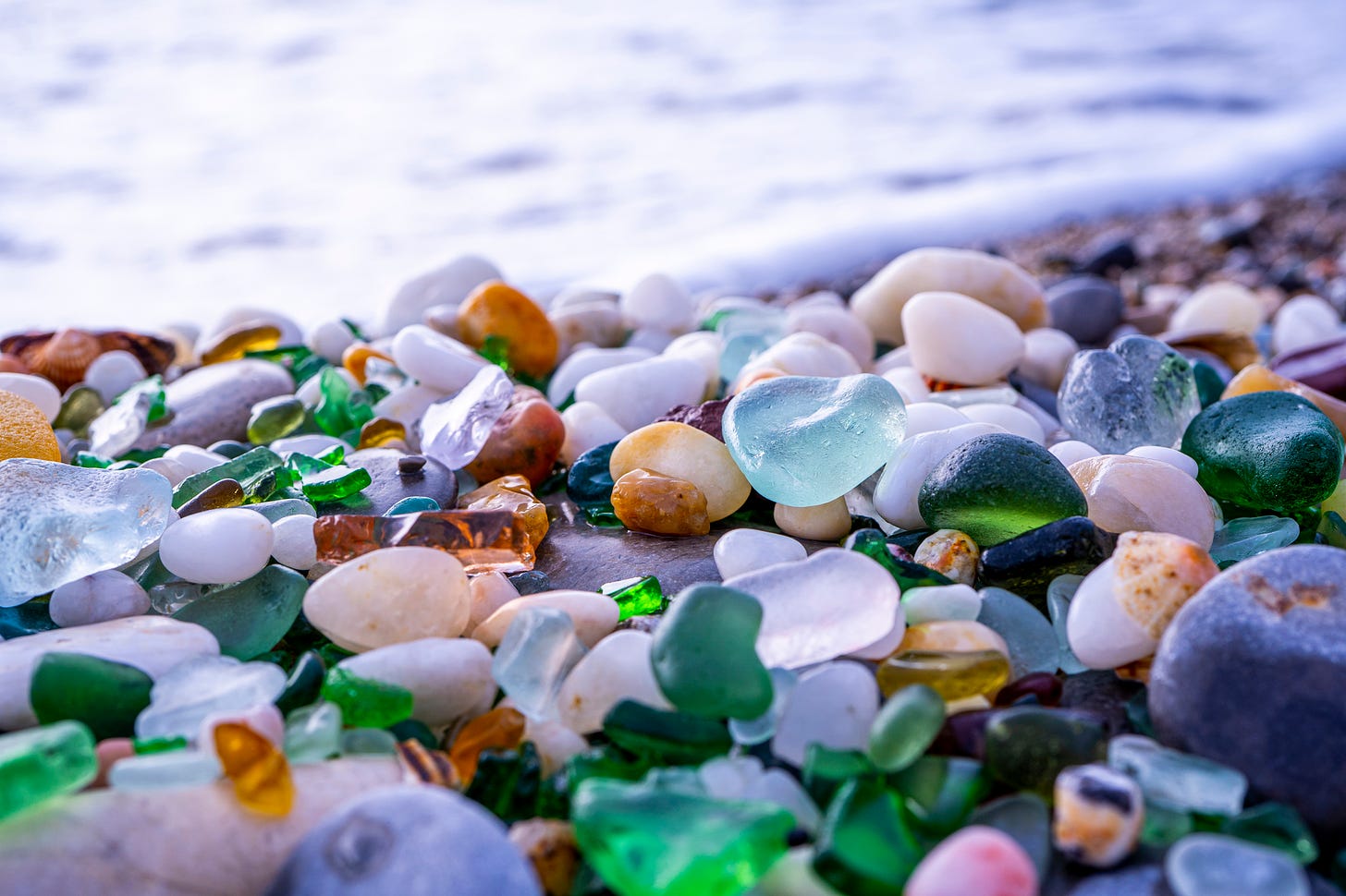 nuggets of aqua and green sea glass on a pebble beach