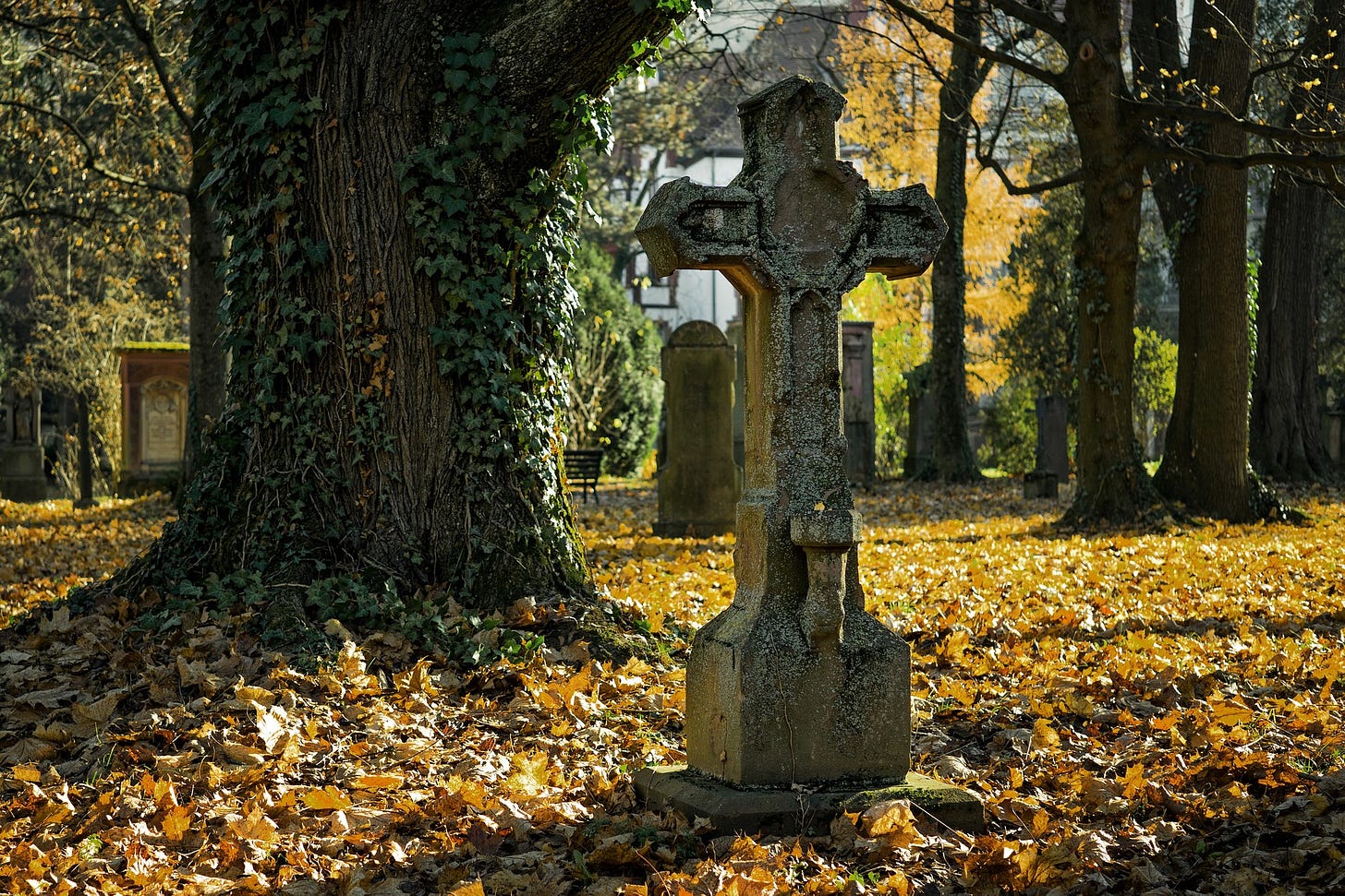 Cross headstone in autumn cemetery