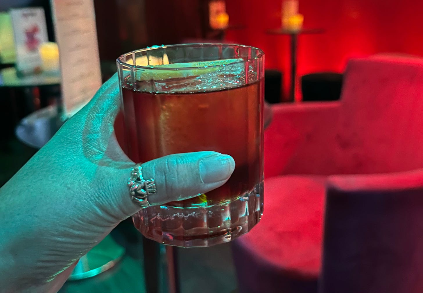 Hand holding a cocktail inside a bar in London.