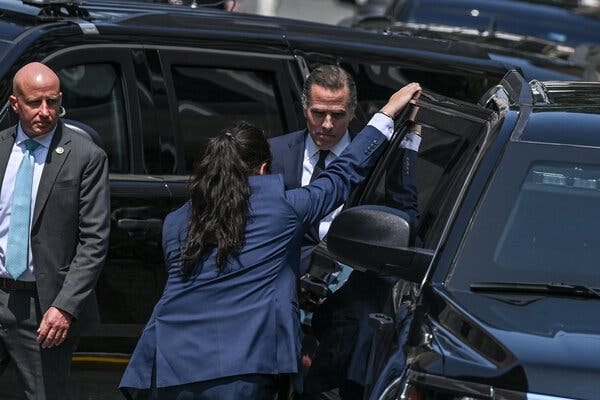 Hunter Biden entering a vehicle. A person is holding the door open for him. 
