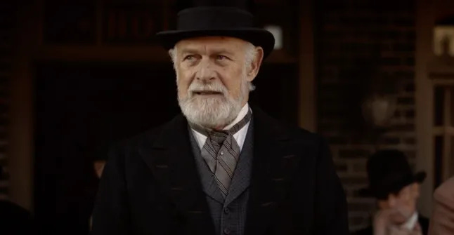 This image shows George Hearst (played by Gerald McRaney) dressed in his finest clothes while standing on Deadwood's main thoroughfare.