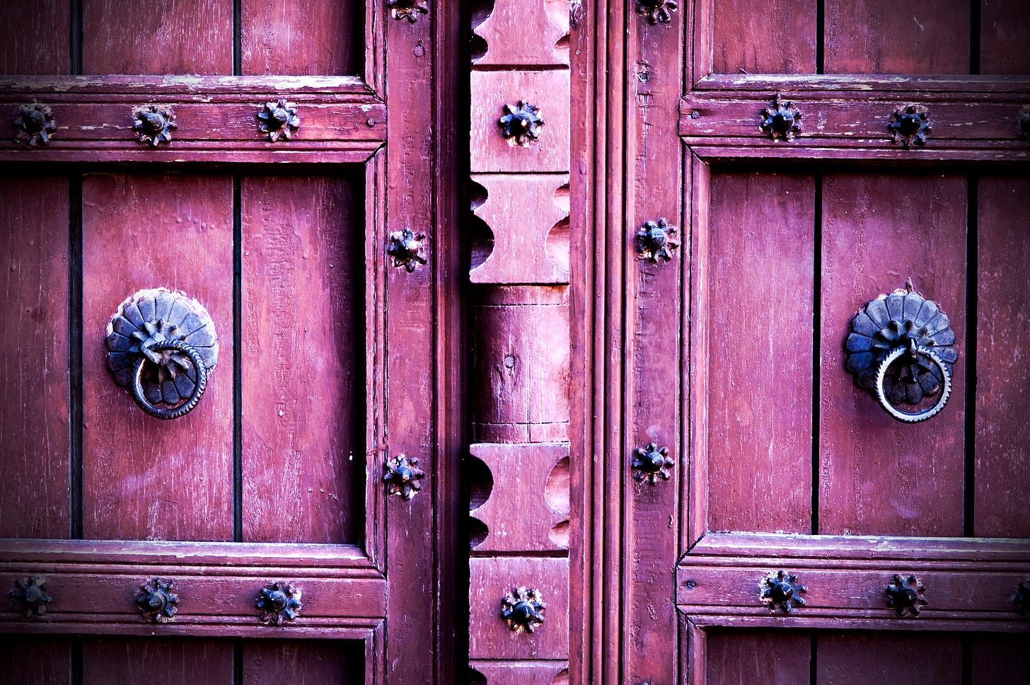 Closeup of a pair of old metal studded purple doors