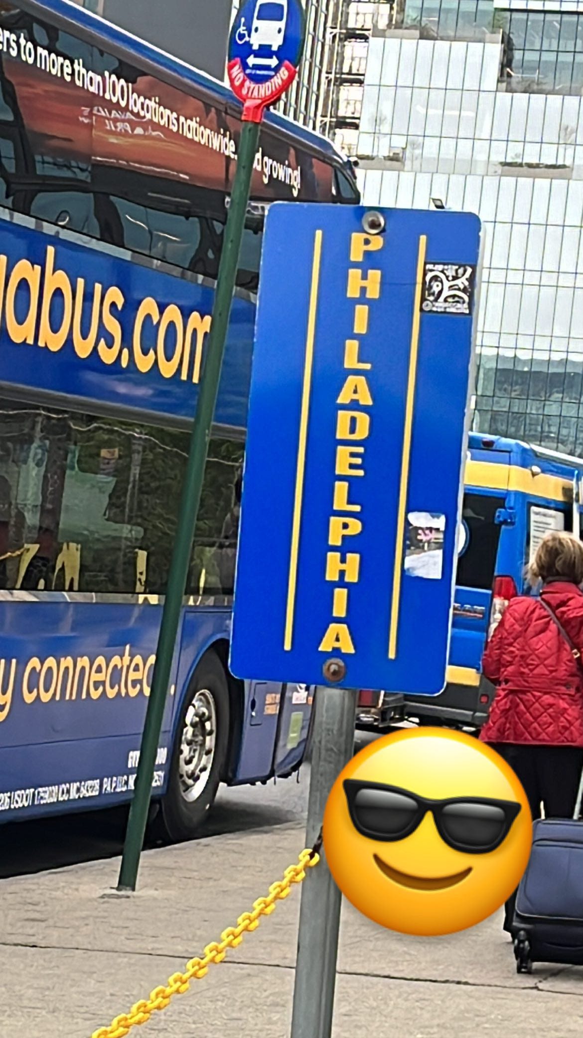 A blue sign that says "Philadelphia" in yellow text. A blue double decker bus is in the background.