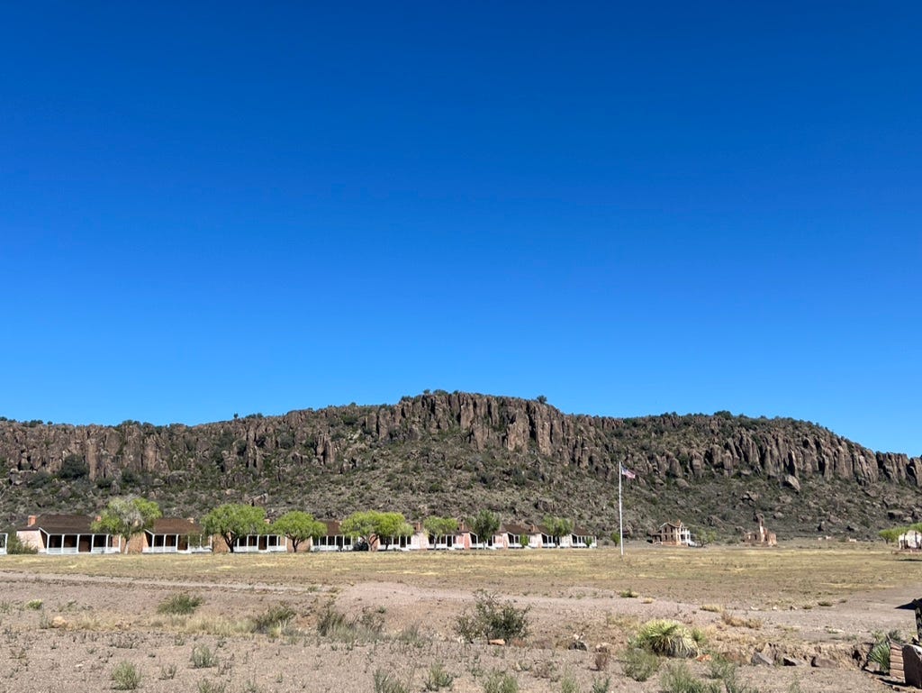 A landscape with a hill and houses with Fort Davis National Historic Site in the background

Description automatically generated