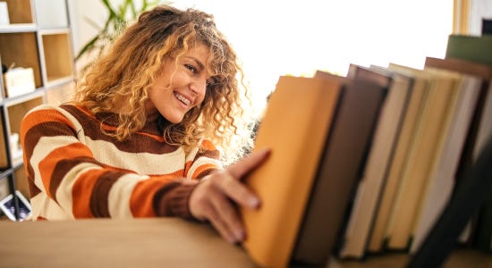 a photo of someone smiling while putting a book on a shelf