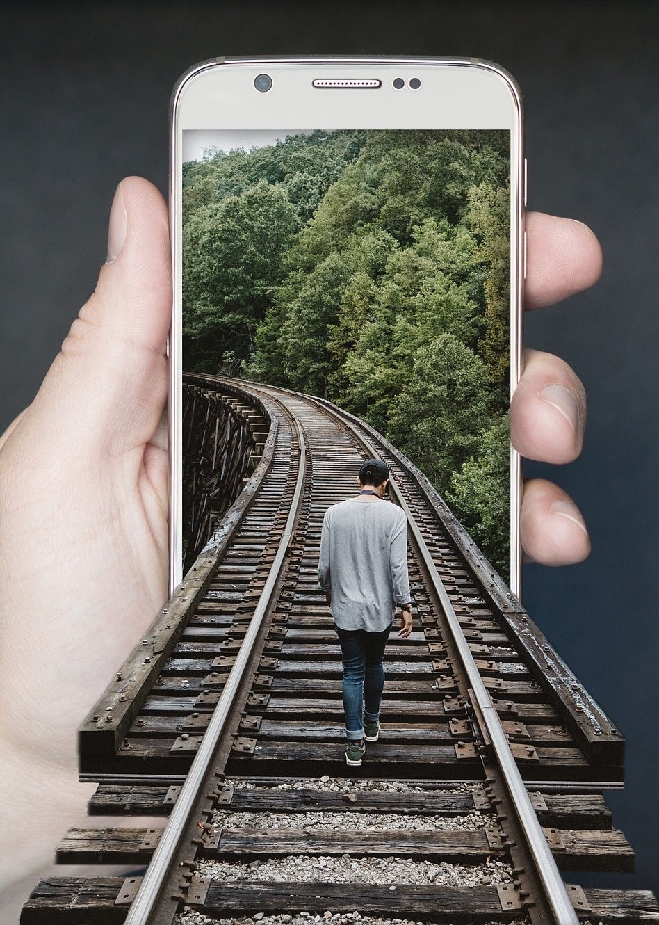 Photo of a man following a railroad track through a cellphone