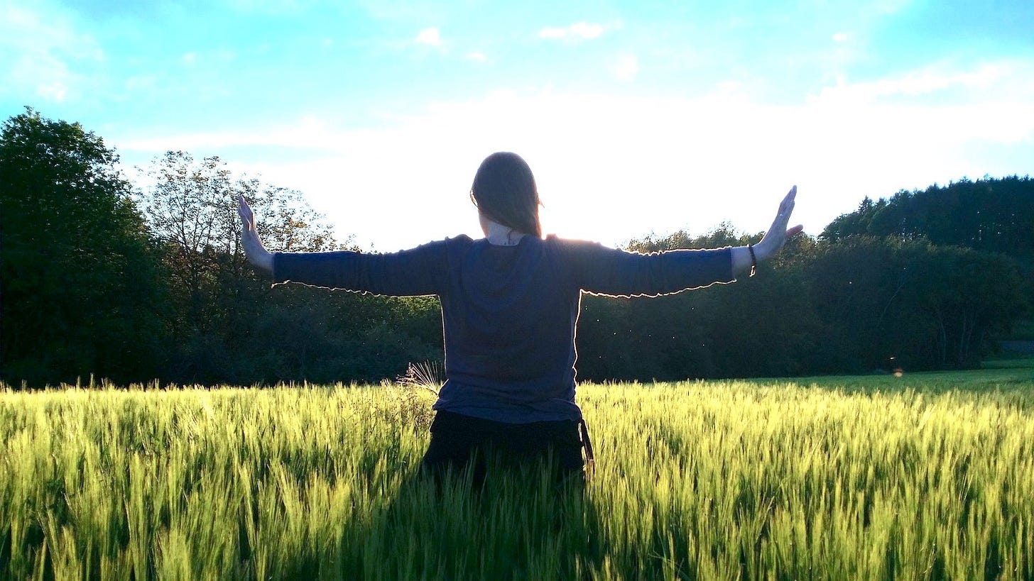 Woman in field outstretching her hands.