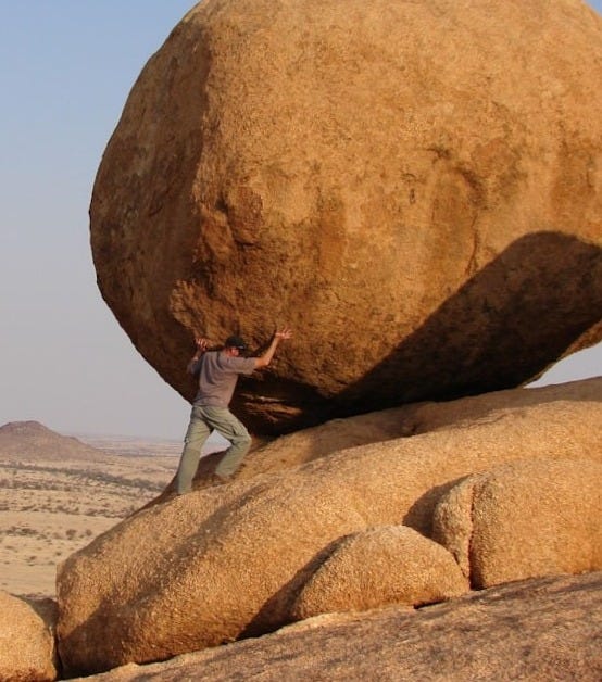 man standing beside rock formation