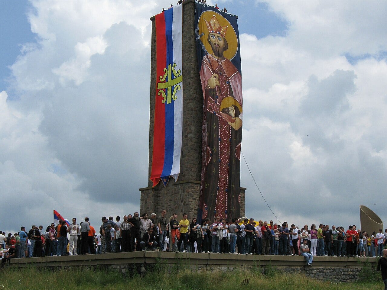 crowds surround a tower with a banner of Saint Prince Lazar Hrebeljanović