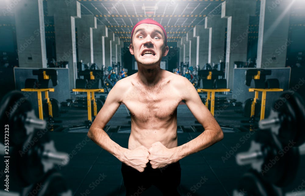 Thin guy poses on workout in gym, dystrophic