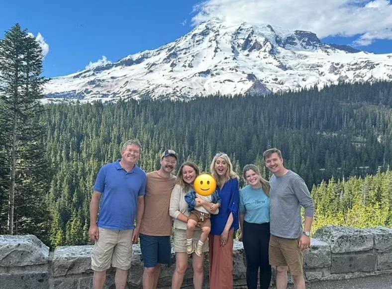 A group of people posing for a photo with a mountain in the background

Description automatically generated