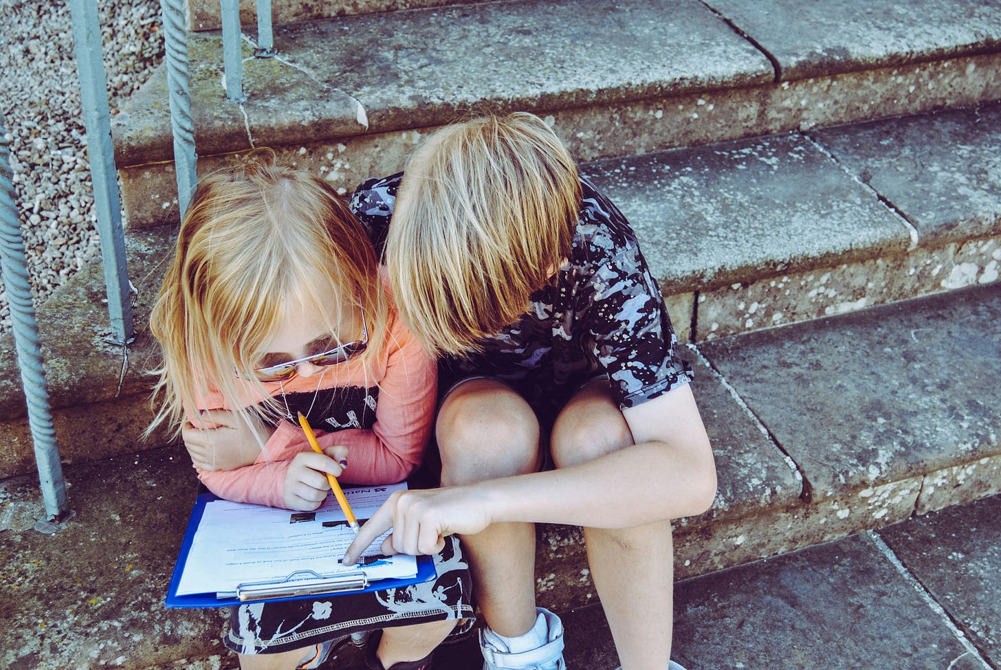 Boy and girl on stone steps looking at information on a clipboard