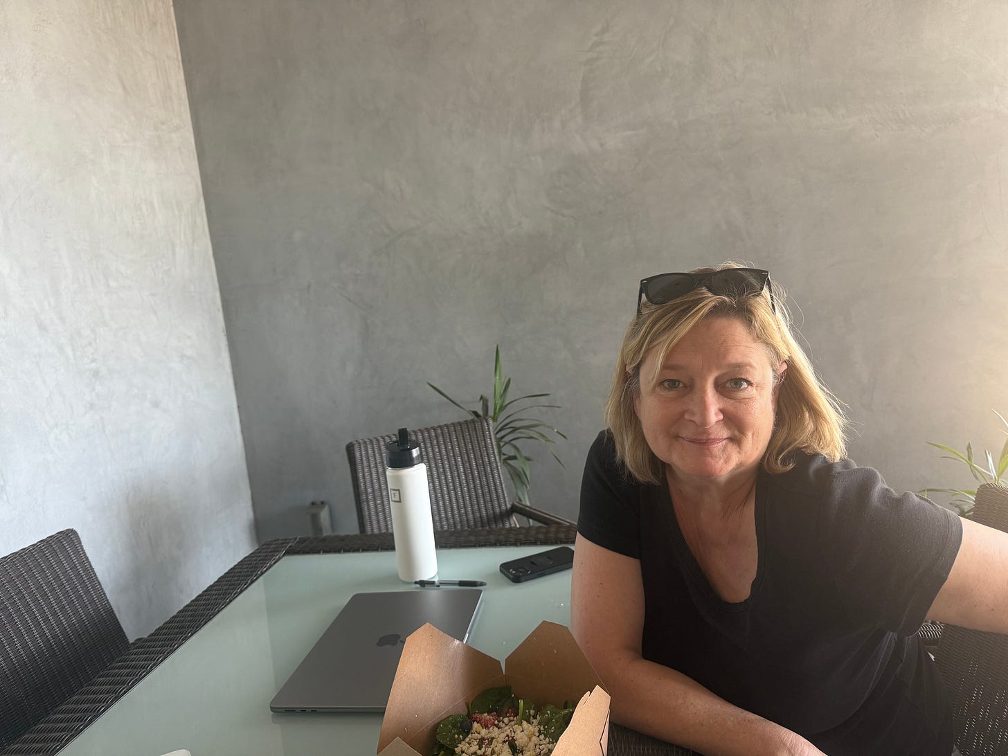 white woman at an outdoor coffeeshop table with a computer, smiling white woman at an outdoor coffeeshop table with a computer, smiling