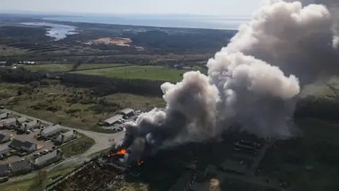 Josh Fryer Aerial footage shows huge plumes of smoke rising high into the sky over the still-blazing site