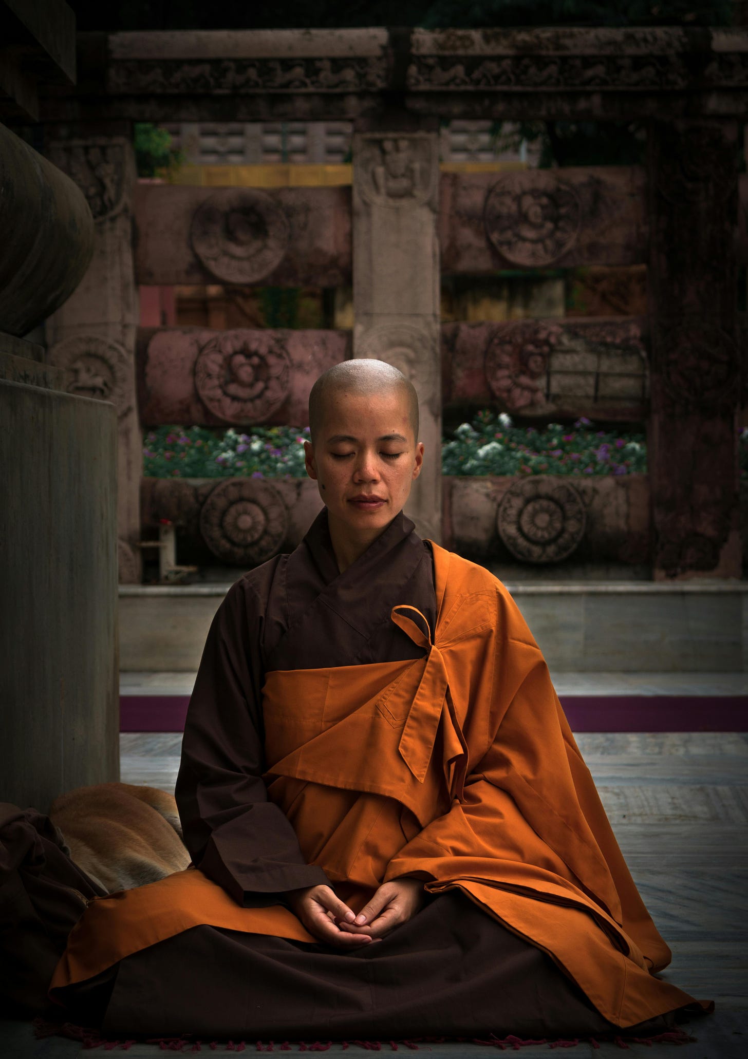Buddhist monk with shaved head sitting in a position implying that they are meditating.