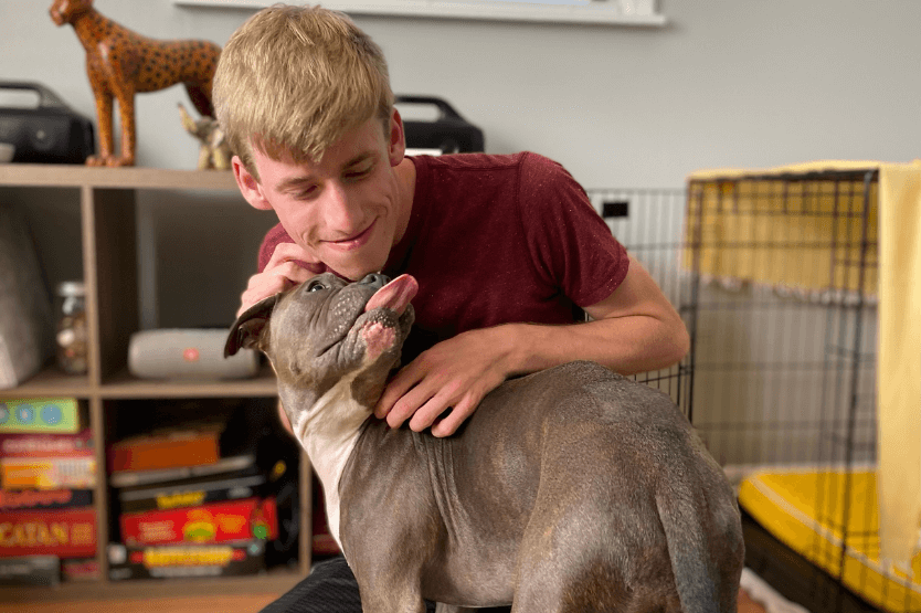 Our first foster, a bully breed mix, licking Sean's face