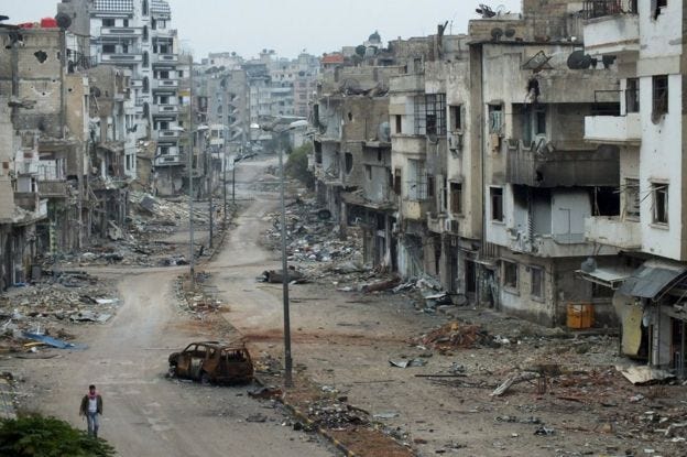 A man walks past damaged buildings along a street at the Khalidiya district of Homs, Syria (19 November 2012)