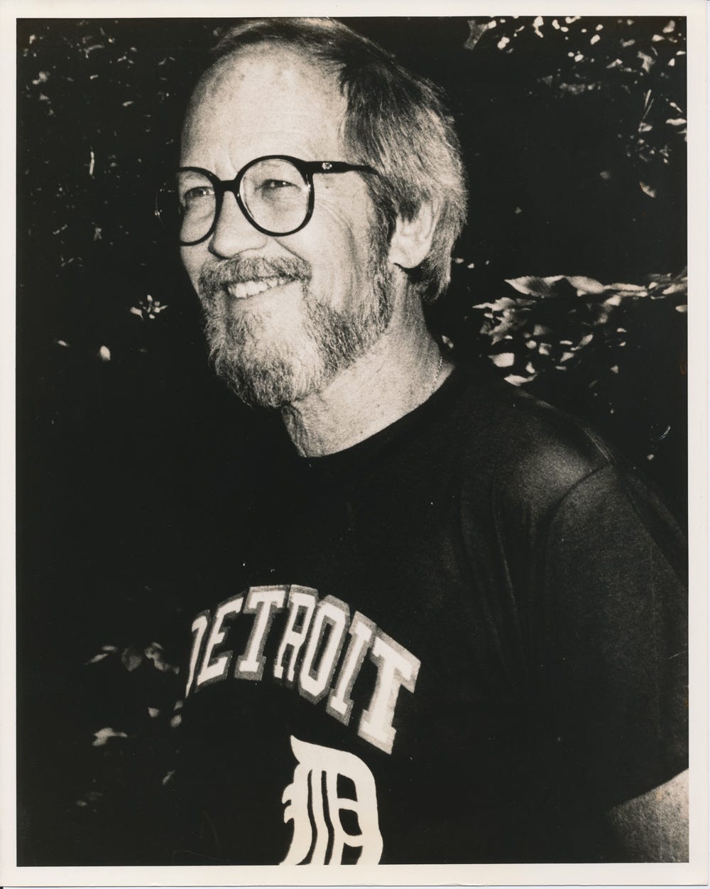 A portrait of Elmore Leonard wearing glasses and a Detroit t-shirt, probably taken around the 1980s