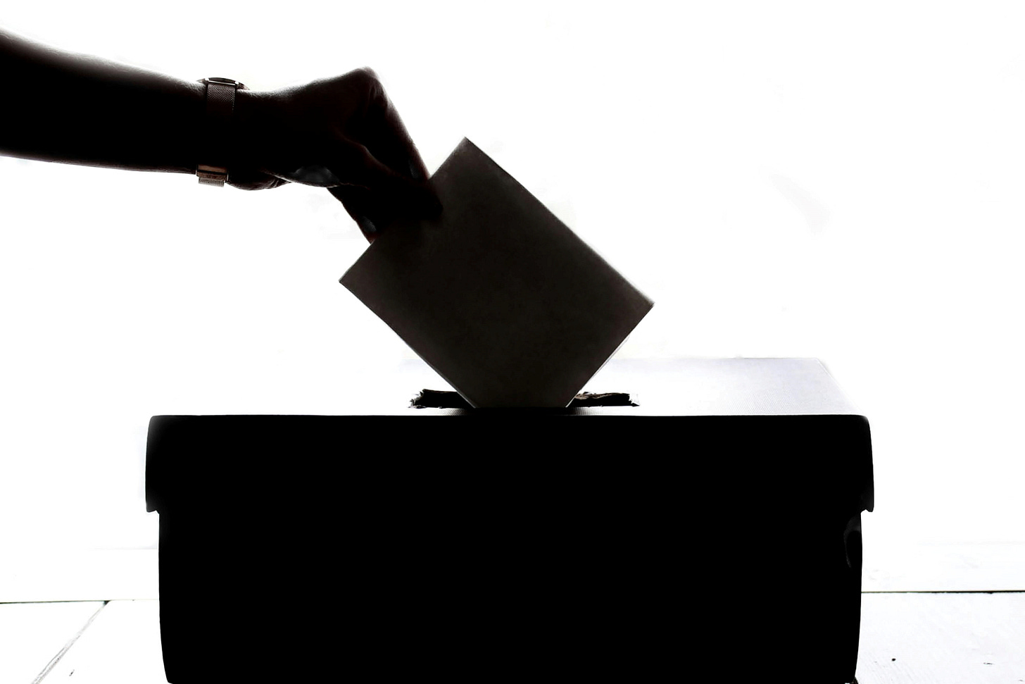 Silhouette of hand dropping envelope into slot on top of a box
